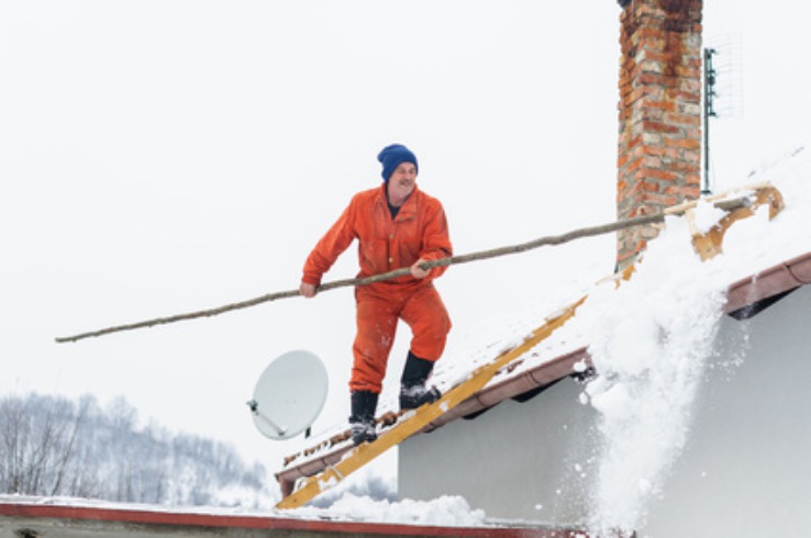 man raking snow from roof - no fall arrest equipment