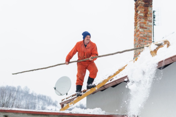 man raking snow from roof - no fall arrest equipment man raking snow from roof - no fall arrest equipment